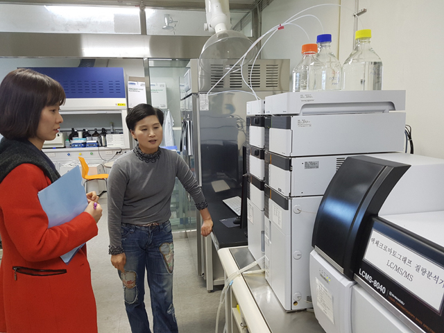 Photograph of two people looking at mass spectrometer.